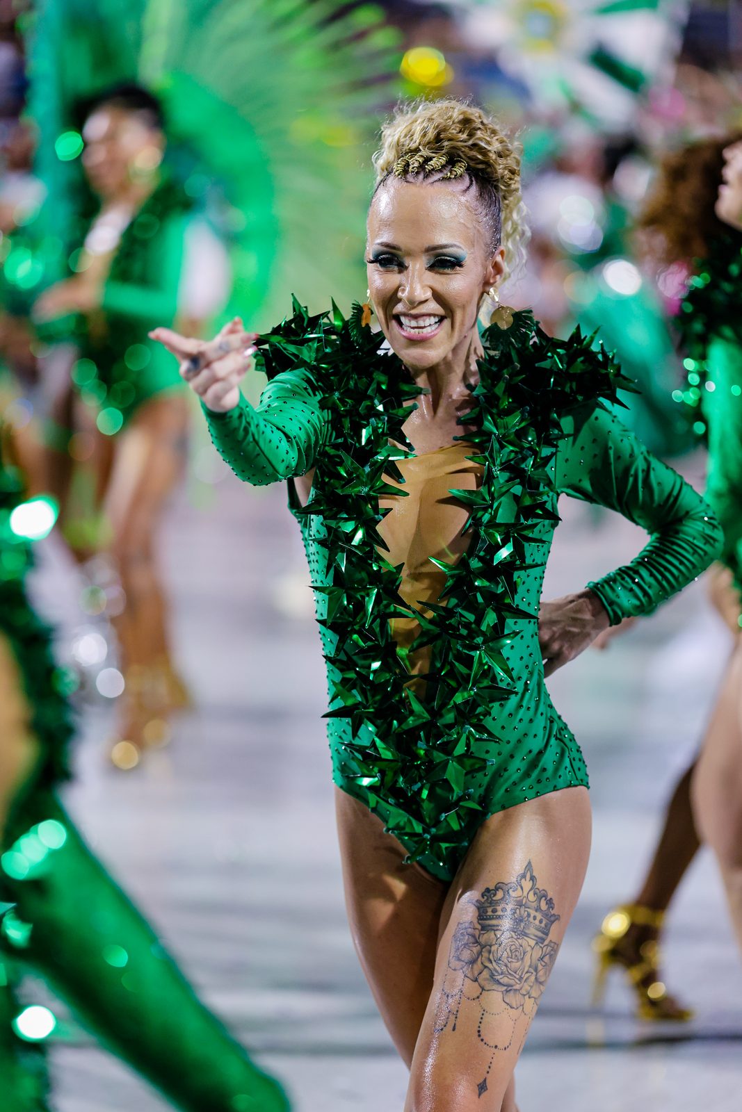 Anna reaching forward in a green costume on the parade avenue